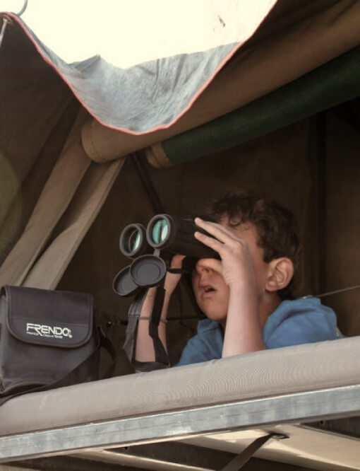 Enfant observant la nature avec des jumelles sous une tente