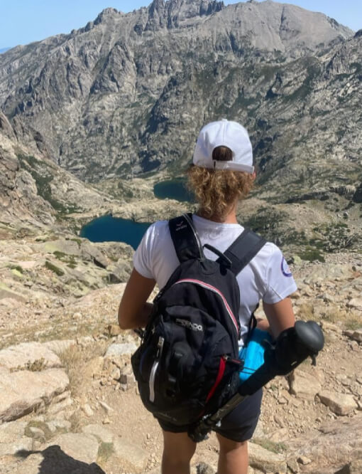 Randonneuse équipée d’un sac à dos face à un lac de montagne et de Bâton Lady Meiji Frendo